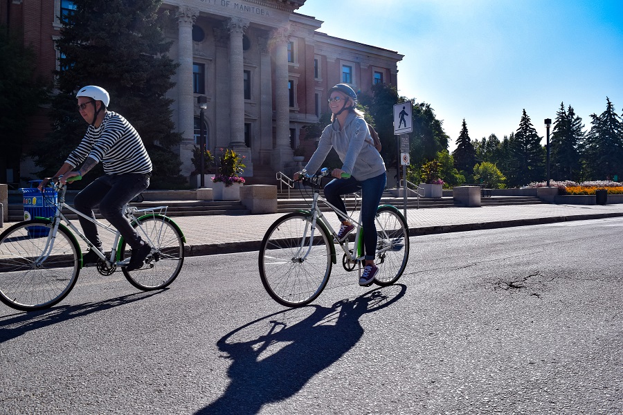 Two people cycling in front of UM Administration